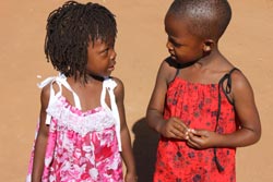 Two tiny girls discuss their dresses